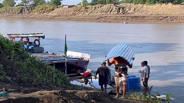 असम में बाढ़ के कारण जलमग्न गांव और घरों के अंदर जमी मिट्टी व मलबे का दृश्य, आपदा प्रभावित लोग राहत शिविरों की ओर पलायन करते हुए।