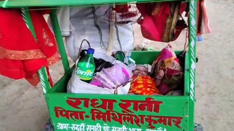 सुल्तानगंज से देवघर मार्ग पर अपनी दो महीने की नवजात बेटी को सोलर पैनल वाली आधुनिक डोली में रखकर दंडवत यात्रा करते शिवभक्त मिथिलेश कुमार की तस्वीर