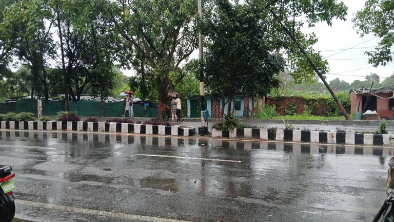 झारखंड के रांची में भारी बारिश और आकाशीय बिजली के अलर्ट के बीच छाए काले बादल और छाता लेकर जाते लोग